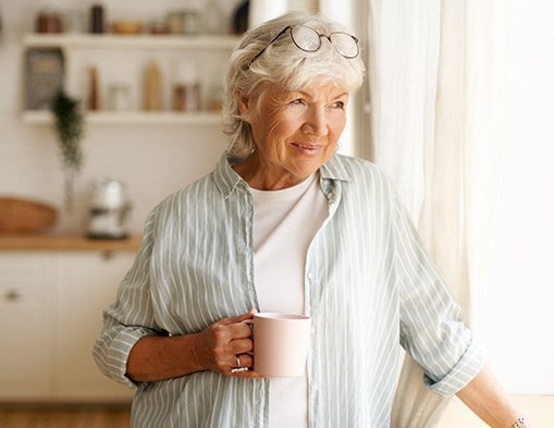 Senior woman looking out window while drinking tea