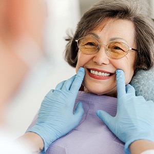 Dentist with blue gloves looking at senior woman's smile