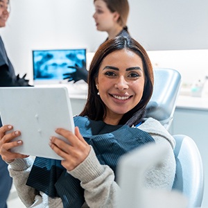 Woman smiling while holding mirror in treatment chair