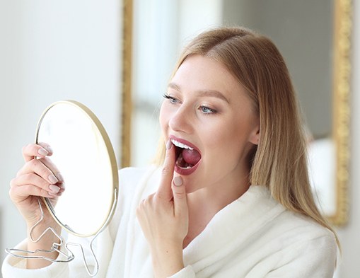 Patient checking teeth in mirror after teeth whitening 