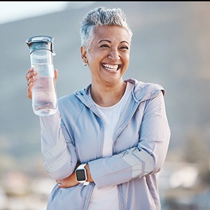 Woman smiling with water bottle on hike outside