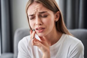 Woman holding mouth in pain.