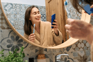 Woman brushing her teeth while reading a blog on her phone